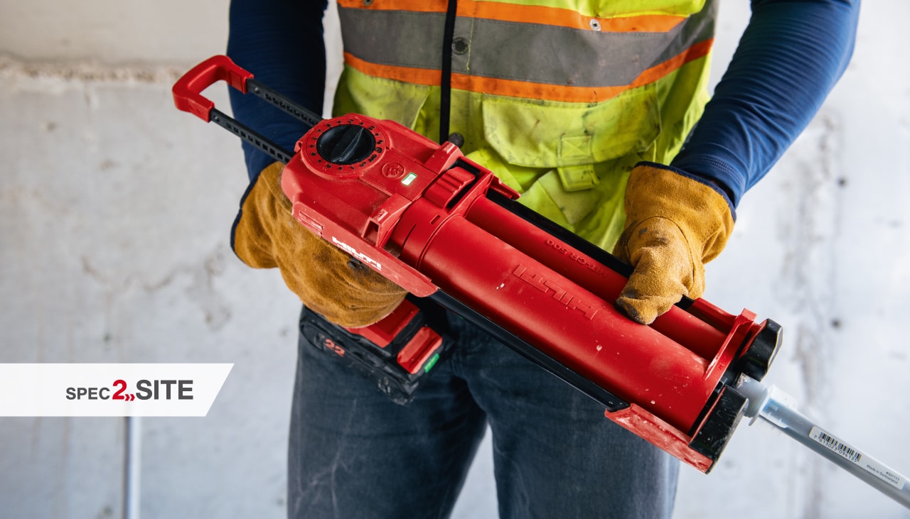 A contractor installs an anchor into concrete